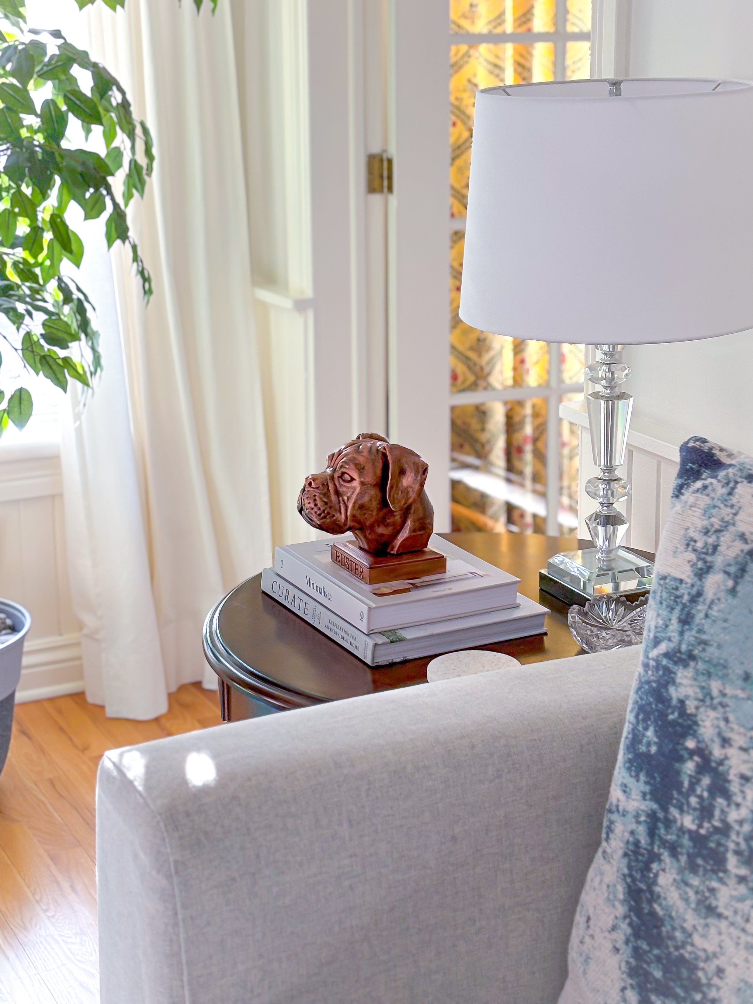 Personalized bronze boxer dog statue displayed on a side table next to a lamp by a sofa